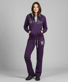 Woman wearing a purple tracksuit with visible branding on a gray background