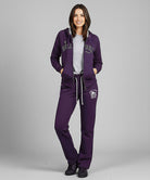 Woman wearing a purple tracksuit with visible branding on a gray background